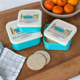 Three blue snack boxes with Periodic Table of Elements print on the lids, displayed on a wooden table.