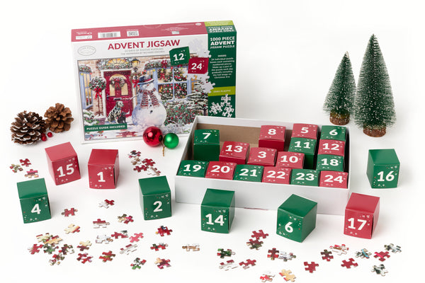 Boxed advent jigsaw with red and green numbered boxes and fern trees and cones and loose jigsaw pieces at the front.  On a whiteground.