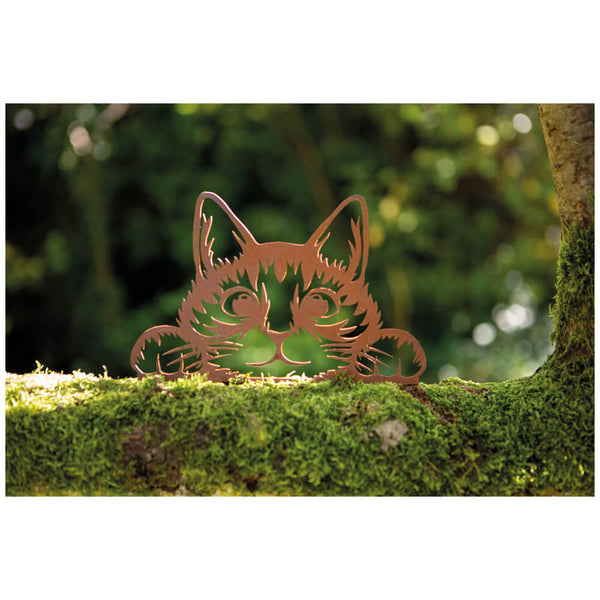 Metal cat-shaped ornament on a mossy surface with a blurred green background.