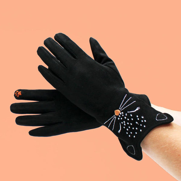 Black gloves with cat design on a peach background