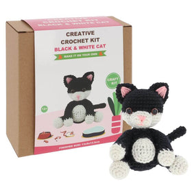 Crochet kit fora black and white cat with pink ears and nose set on a white background.