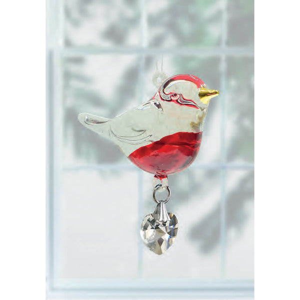 Decorative bird ornament with red and white colors hanging against a blurred window background.