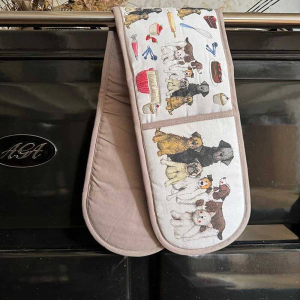 Oven gloves featuring dogs hung over an Aga oven on a black background.