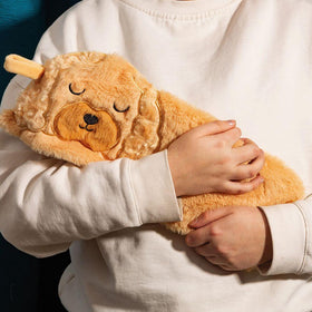 Person holding a light brown dog shape hot water bottle with furry material.