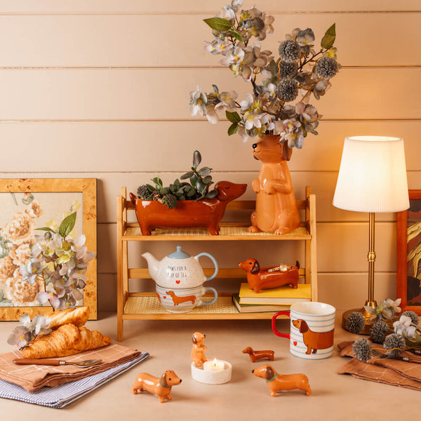 Decorative items including a teapot, mug, and small dog figures on a wooden shelf against a wooden wall.