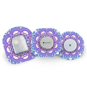 Three glucose monitoring devices with decorative blue mandala CGM patches on a white background