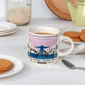 A ceramic mug with a vintage London Underground poster design featuring an event at Wembley Stadium, with the London Transport Museum Collection logo.