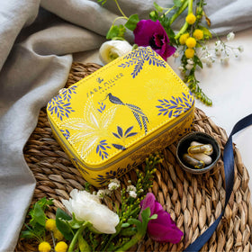 Yellow medication organiser box with floral design on a woven mat with flowers around