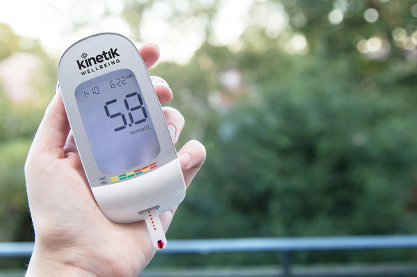 A person with diabetes holding the Kinetik Wellbeing blood glucose meter and test strip.