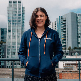 A person wearing a dark blue hoodie with orange drawstrings, featuring the Diabetes UK logo, standing in front of a cityscape.
